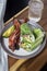 Vertical closeup shot of the lettuce wraps with bacon and avocado on a plate with a glass of water