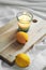 Vertical closeup shot of a litten candle and oranges on a wooden board, on a white comforter