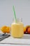 Vertical closeup shot of a mason jar of fresh natural peach juice or nectar with a tube on a table