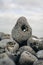 Vertical closeup shot of a pebble rock with a hole on a pile of rocks on a blurred background