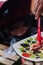 Vertical closeup shot of a person holding a plate and a red kitchen tong with a blurry background