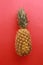 Vertical closeup shot of a pineapple on a red surface