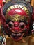 Vertical closeup shot of a scary colorful tribal mask with its teeth out and bulging eyes