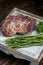 Vertical closeup shot of the seasoned steak on a tray with greens on a wooden table