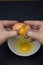 Vertical closeup shot of separating egg whites from yolks with a black background