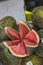 Vertical closeup shot of sliced fresh ripe watermelon on a pile of melons