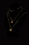 Vertical closeup shot of two golden necklaces on a black mannequin with a black background