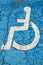Vertical closeup shot of a white disabled person sign painted on a blue cracked surface