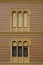 Vertical closeup shot of windows with opened and closed shutters on the renovated yellow building