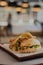 Vertical closeup of a sliced burger on a black board in a restaurant, blurred background