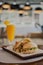 Vertical closeup of a sliced burger and a glass of orange juice in a restaurant, blurred background