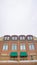 Vertical Cloudy sky and string lights over a building with brick wall and snowy balcony