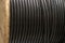 Vertical coils of black industrial wires. Many turns of the main electrical cable is closeup. Roll of outdoor fiber optic signal