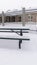 Vertical Cold winter day at a park with picnic tables and benches covered with snow