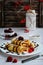 Vertical composition. Appetizing pancakes with chocolate filling and syrup on a white plate, raspberries and