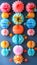 Vertical composition of colorful paper decorations hung against a light blue wall.DIY art installation
