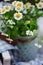 Vertical composition of fresh camomile flowers picked in vintage jar