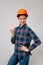 Vertical, of a confident cheerful builder woman on a light background, showing that everything is fine