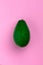 Vertical creative pink layout of bright ripe green avocado
