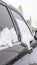 Vertical crop Exterior view of a shiny black car with fresh snow on the tinted windows