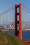 A vertical crop of the North Tower of the Golden Gate Bridge with the afternoon sun shining on San Francisco in the background