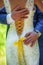 Vertical cropped picture of couple groom in blue suit holding back of bride in beautiful lace wedding gown with yellow ribbon.