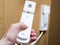 Vertical cropped view of woman hand holds the intercom receiver headset, standing in apartment hall