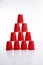 Vertical of a cup pyramid made of red disposable plastic cups against a white background