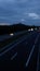 vertical defocused and blurred video of cars driving along a highway at night, blue hour