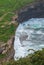 Vertical detail of cliff with people and cows with rough sea