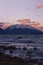 Vertical distant view of a snow-covered mountain at the coast of a sea at sunset
