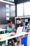 Vertical of diverse male teacher and schoolboy using laptop at his desk in classroom, copy space