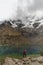 Vertical drone shot of a caucasian hiker hiking near a small mountainous lake in Peru