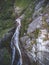 Vertical drone shot a waterfall flowing from the cliffs covered with trees in the daytime