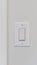 Vertical Electrical rocker light switch on white wall against blurry door background