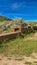 Vertical Elevated wooden bike tracks amid bushes and grasses on a hill under blue sky