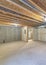 Vertical Empty unfinished large basement with concrete flooring and wooden frames