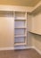 Vertical Empty walk-in closet with warm color lighting and shelving units