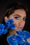 Vertical eye catching charming, seductive brunette woman with blue evening make up and flower twig near face. Copy space