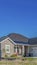 Vertical Facade of home with concrete driveway in front of three garage doors and porch