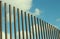 Vertical fence and sky clouds background  with clean blue sky and white clouds. Unusual line up fence architecture composition for