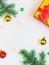 vertical festive background: two green branches, gold and red Christmas decorations, beads and a gift box with a bow. Copy Space