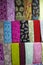 Vertical filled frame close up shot of varieties of colorful pashmina fabric shawls and scarves hanging on display on a shelf of a