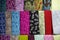 Vertical filled frame close up shot of varieties of colorful pashmina fabric shawls and scarves hanging on display on a shelf of a