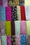 Vertical filled frame close up shot of varieties of colorful pashmina fabric shawls and scarves hanging on display on a shelf of a