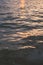 Vertical filled frame full screen desktop wallpaper shot of evening calm sea at dusk with orange sun reflection that makes the