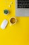 Vertical flat lay minimal home office yellow workspace. Silver laptop and cup of tea. Top view work at home concept