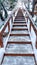 Vertical Focus on stairs with grate treads and metal handrails against snow covered hill