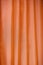 Vertical folds on orange organza curtains