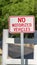 Vertical frame Close up view of a No Motorized Vehicle sign against a road with a white gate